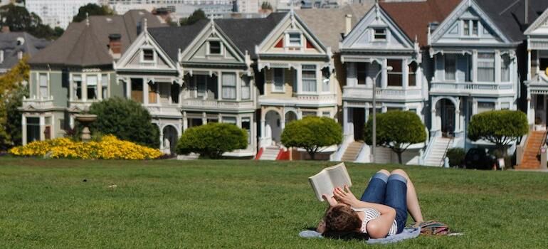 A woman reading a book while lying on the grass