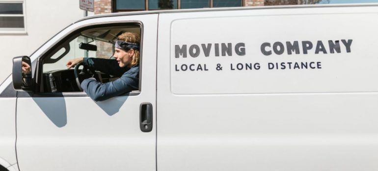 Moving company van with driver seated inside waiting for loading.