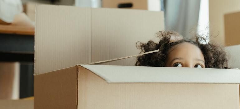 A little girl peeking out of a moving box