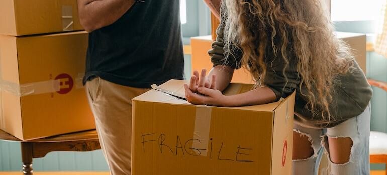 A couple standing around a moving box with fragile written on it