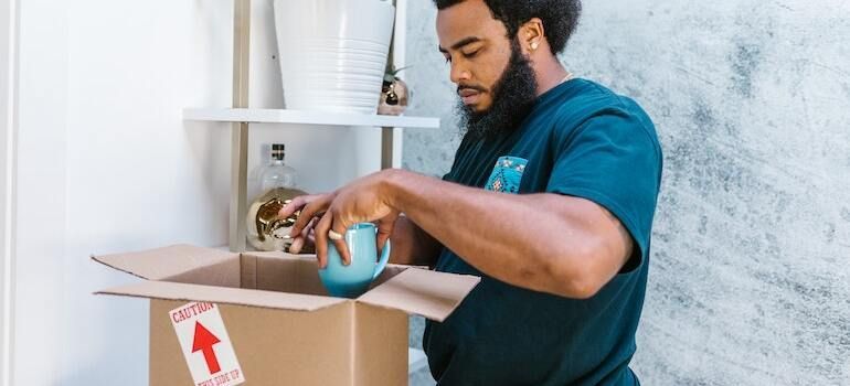 A mover packing a cup into a moving box