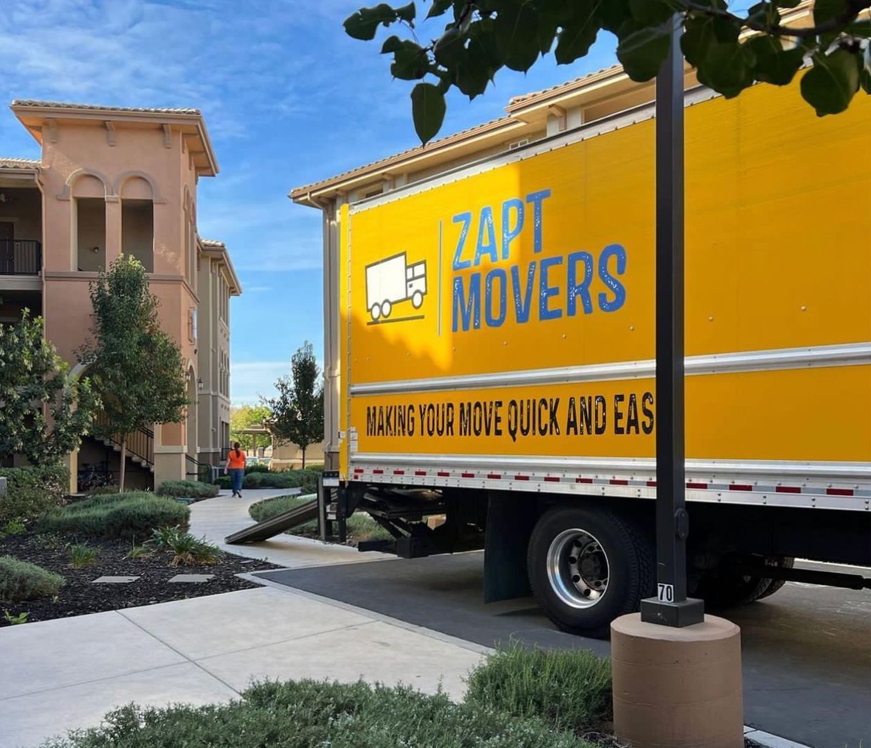 A yellow z4pt movers truck is parked in front of a building