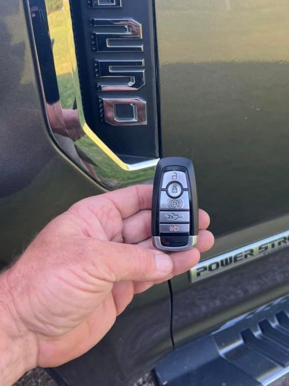 A person is holding a remote control in front of a ford truck