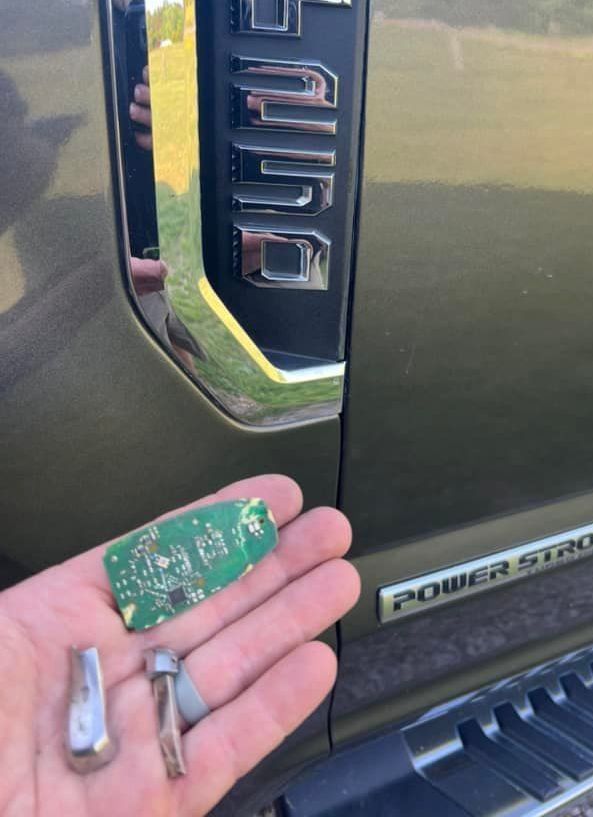 A person holding a key in front of a ford truck