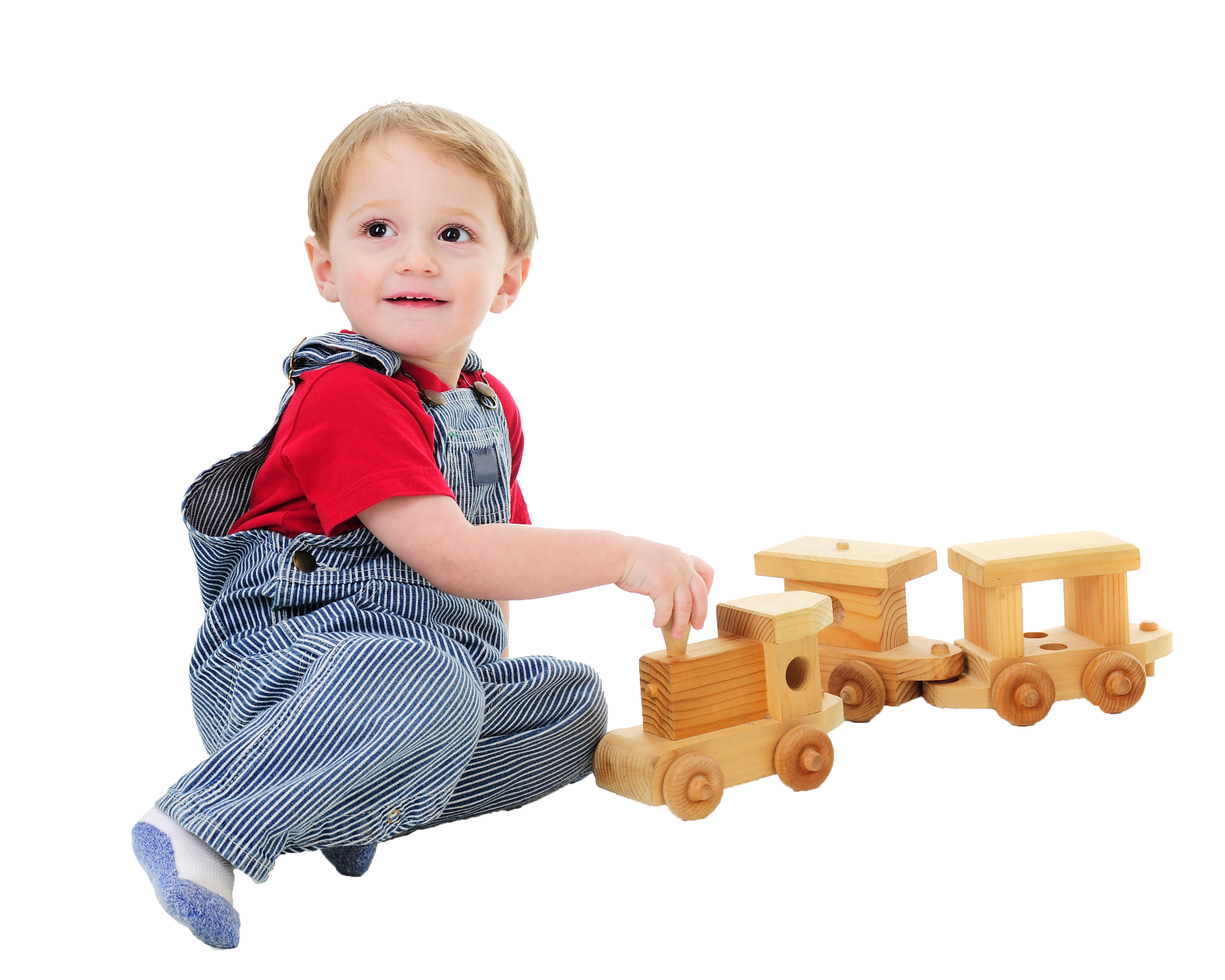 Child in overalls playing with a wooden toy train, smiling, white background. Child in overalls playing with a wooden toy train, smiling, white background.