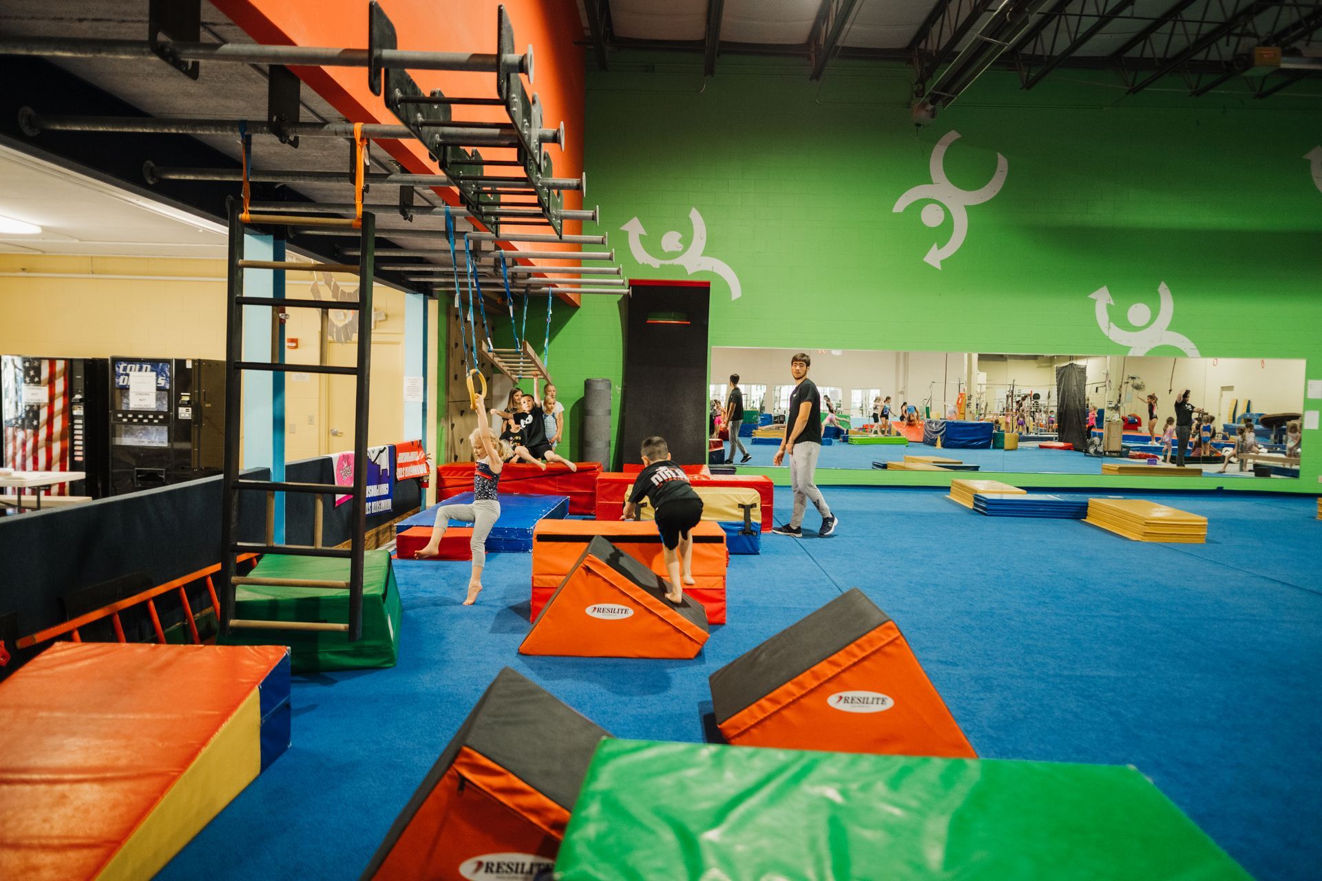 A group of people are playing in a gym with a green wall.