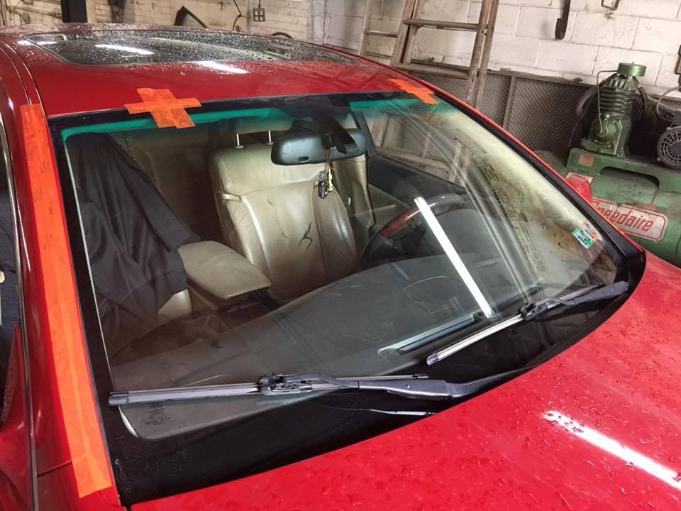 Red car with windshield taped, wipers up, inside visible.