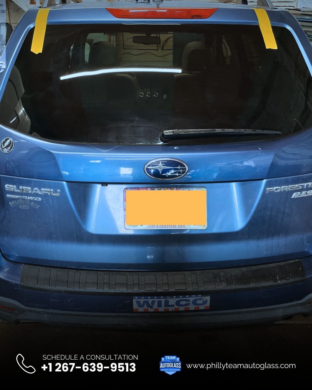 Blue Subaru Forester rear view with yellow tape, license plate blurred, and wiper.