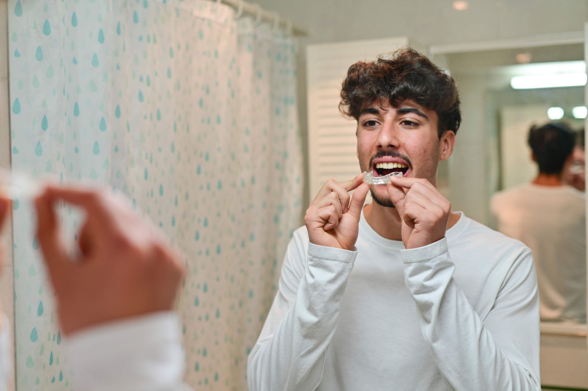 A man is looking at the mirror, putting on an overnight dental splint.