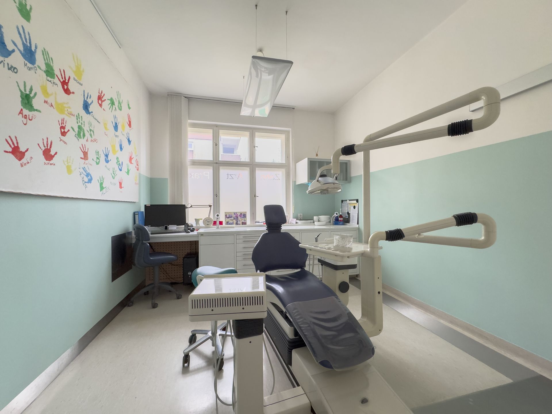 Helles Prophylaxe-Zimmer mit bunten Handabdrücken an der Wand in der Zahnarztpraxis