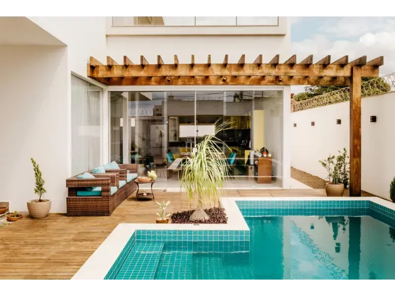 Poolside patio with pool, seating, and wooden pergola.