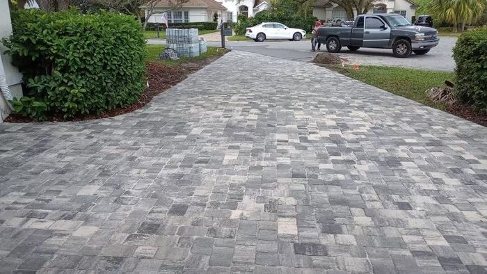 A pavers driveway with a sidewalk in the background