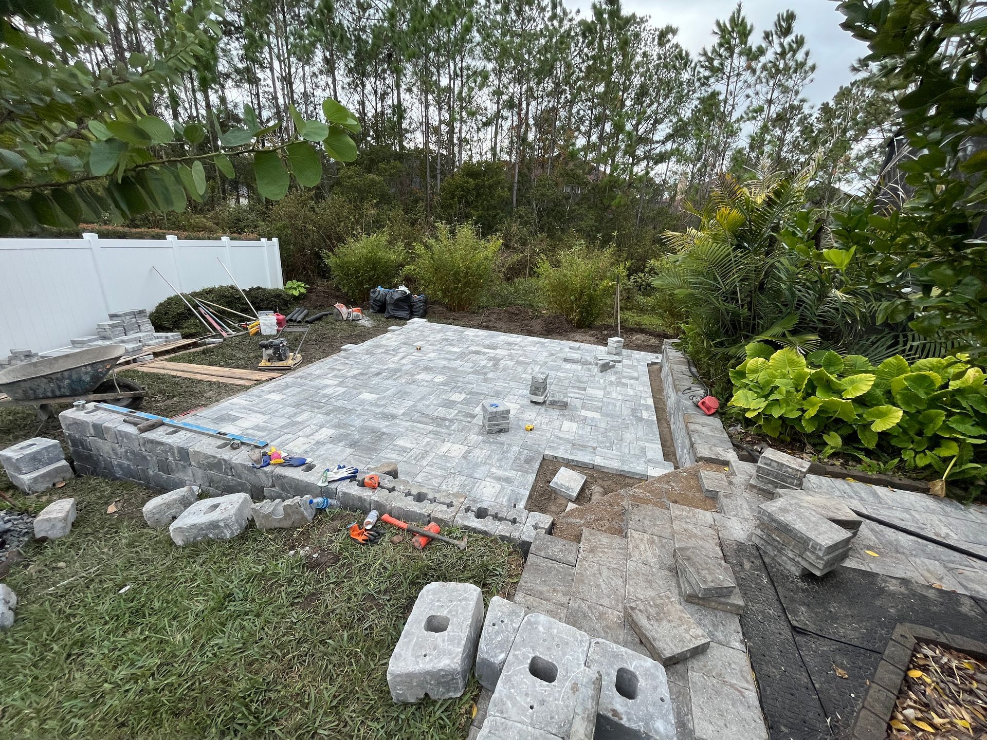 A man is laying pavers on a sandy surface.