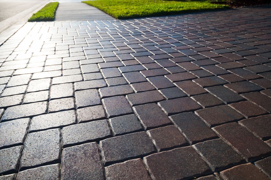 A pavers driveway with a sidewalk in the background