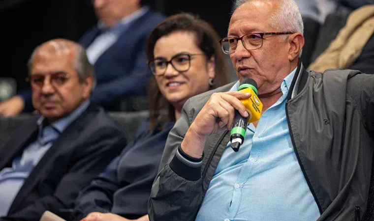 Um homem está segurando um microfone na frente de um grupo de pessoas.