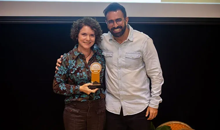 Um homem e uma mulher estão de pé um ao lado do outro segurando um troféu.