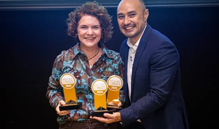 Um homem e uma mulher estão segurando troféus nas mãos.