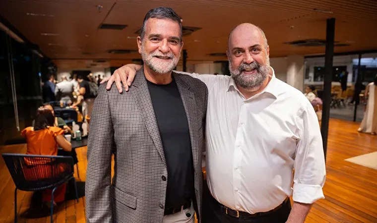 Dois homens estão posando para uma foto juntos em uma sala.