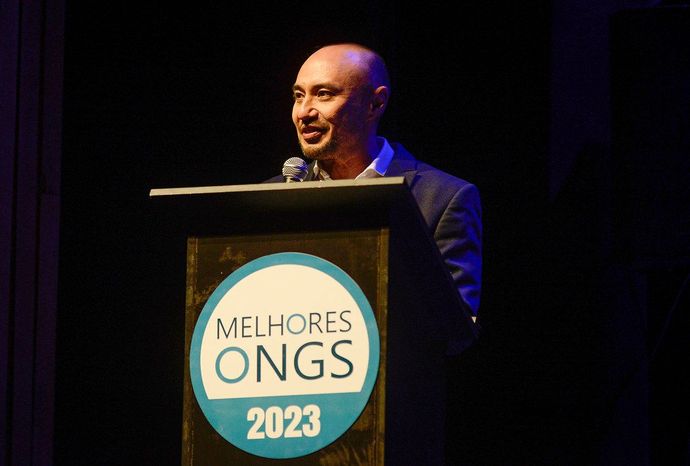 Um homem está em um pódio com uma placa que diz melhores ongs 2023