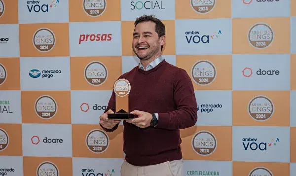Um homem está segurando um troféu em frente a uma parede com logotipos nele.