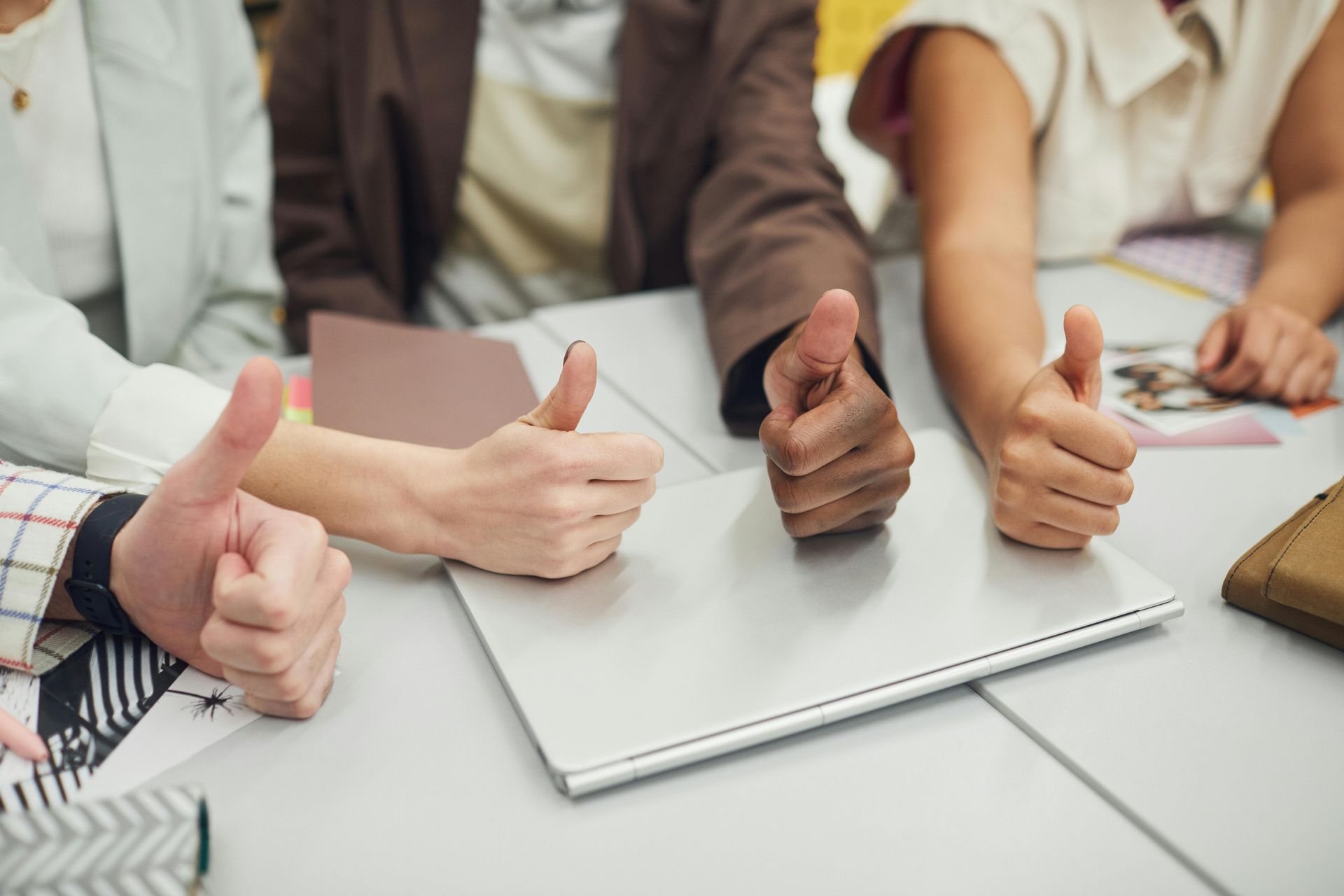 Um grupo de pessoas está sentado à mesa fazendo sinal de positivo.