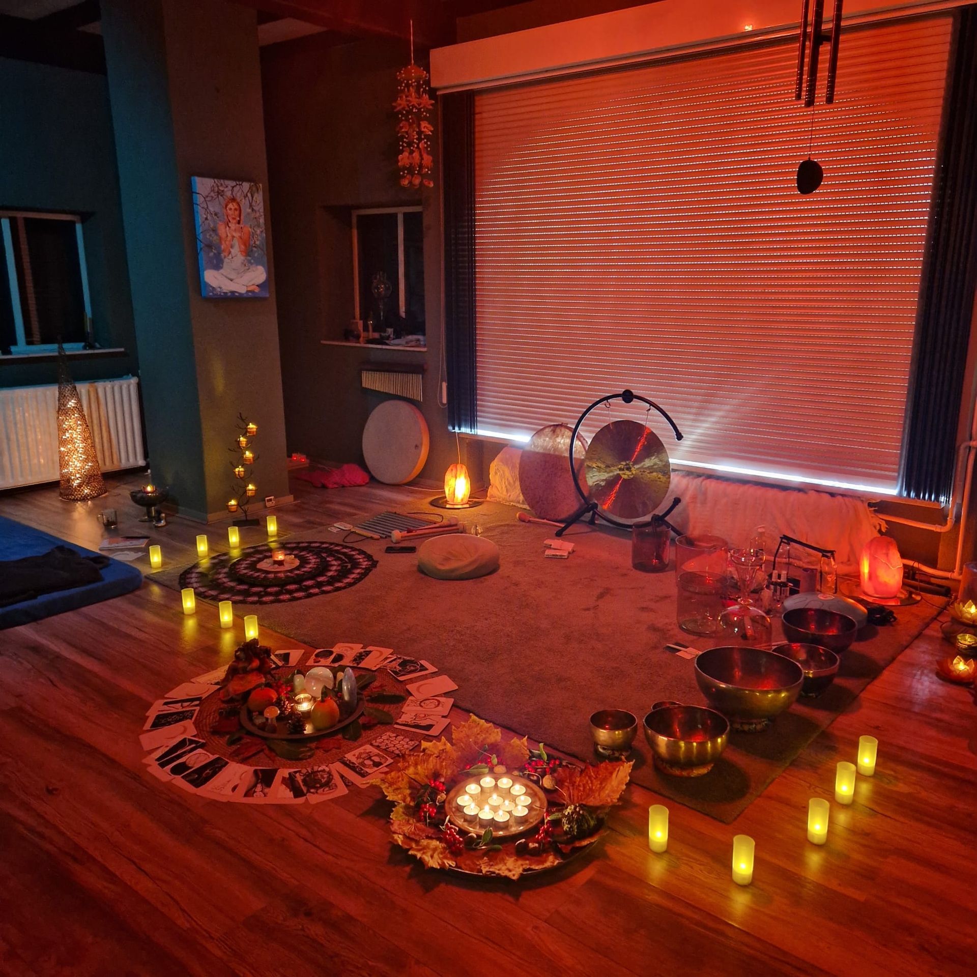 Een meditatieruimte bij kaarslicht, met een gong, klankschalen en tapijten, schemerig verlicht en uitnodigend.