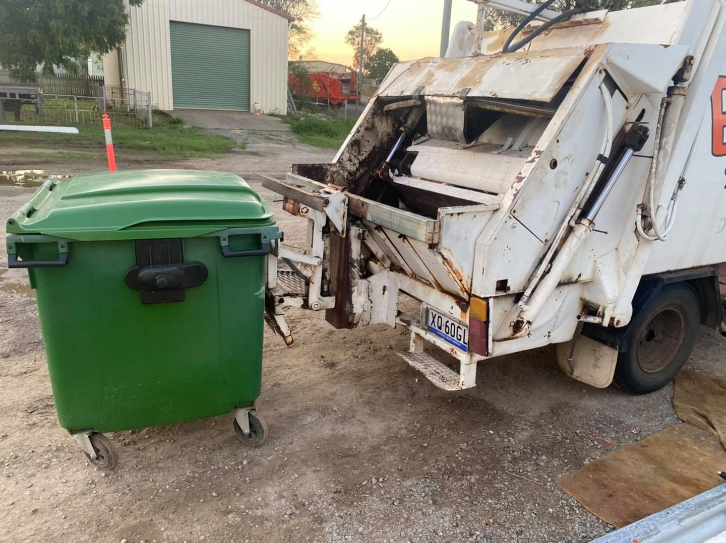 Green Trash Bin Beside a White Garbage Truck — Bob’s Trailer Trash in Gracemere, QLD