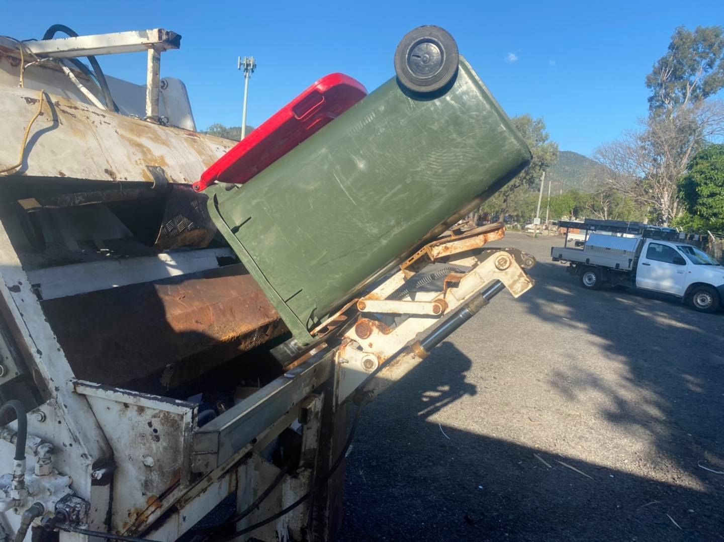 Garbage Truck Emptying a Green and Red Bin Outdoors — Bob’s Trailer Trash in Gracemere, QLD