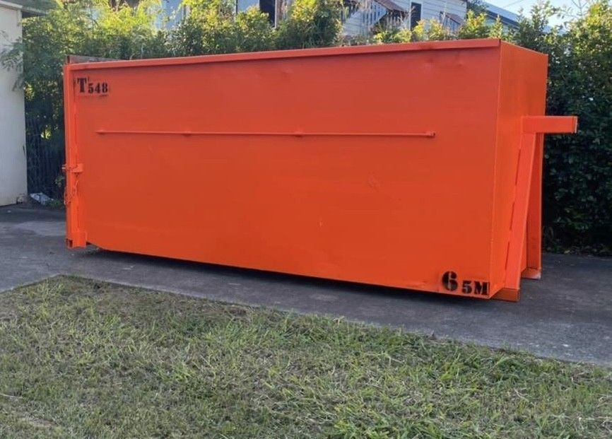 Orange dumpster on a concrete driveway