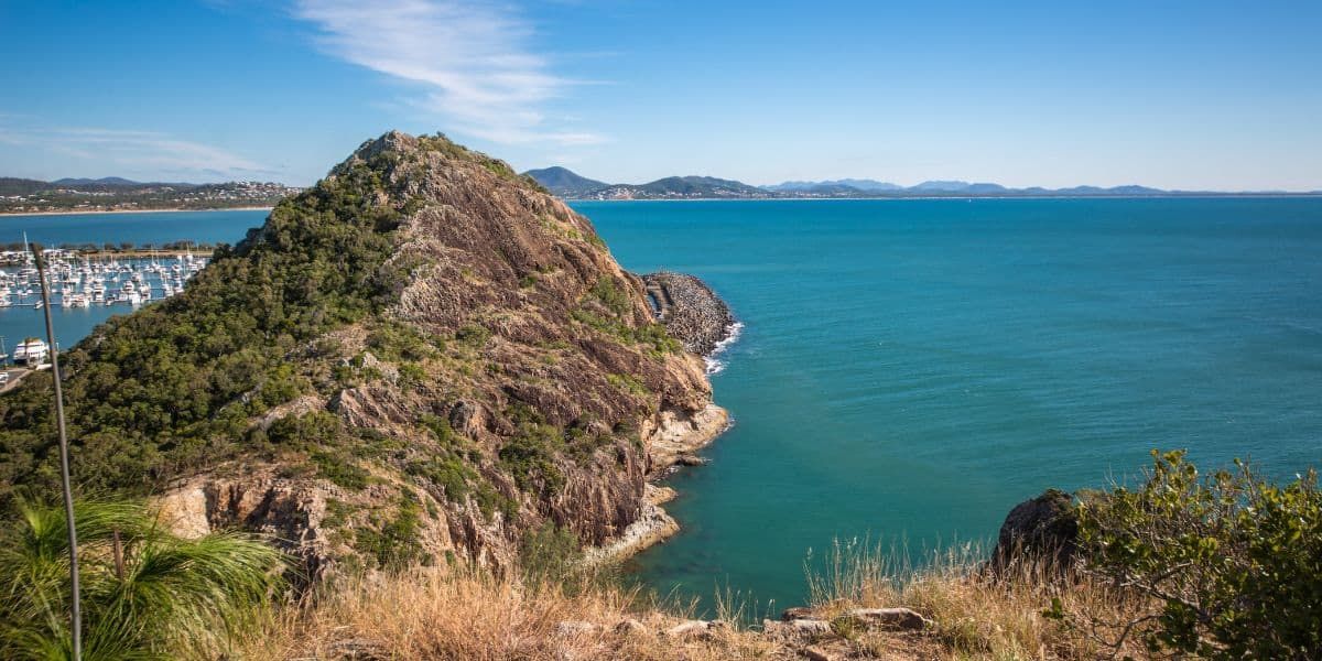 Rocky Island Jutting Into Turquoise Ocean, Under a Clear Blue Sky — Bob’s Trailer Trash in Yeppoon, QLD