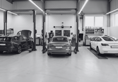 Modern multi-bay European auto repair shop with Audi, Mercedes-Benz, and Tesla vehicles