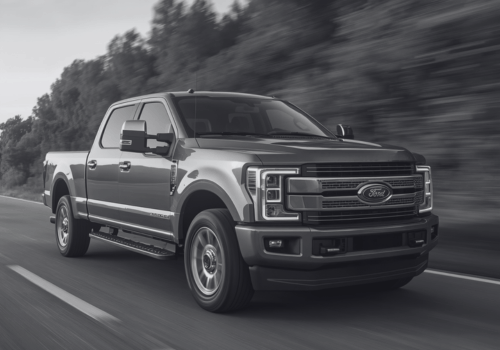 Black and white image of a Ford pickup truck driving on a highway with motion blur.