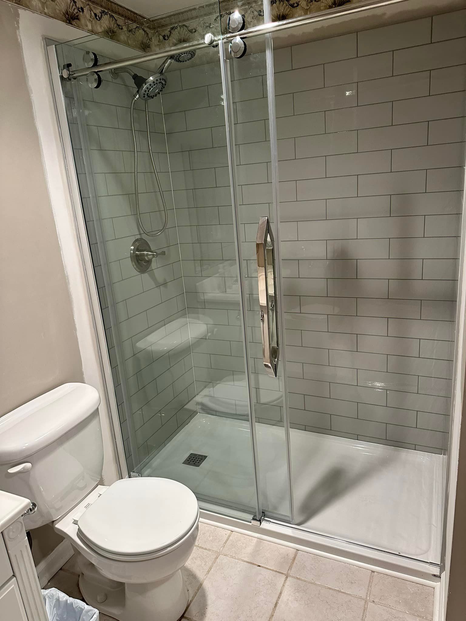A bathroom with a toilet , shower and sliding glass door.