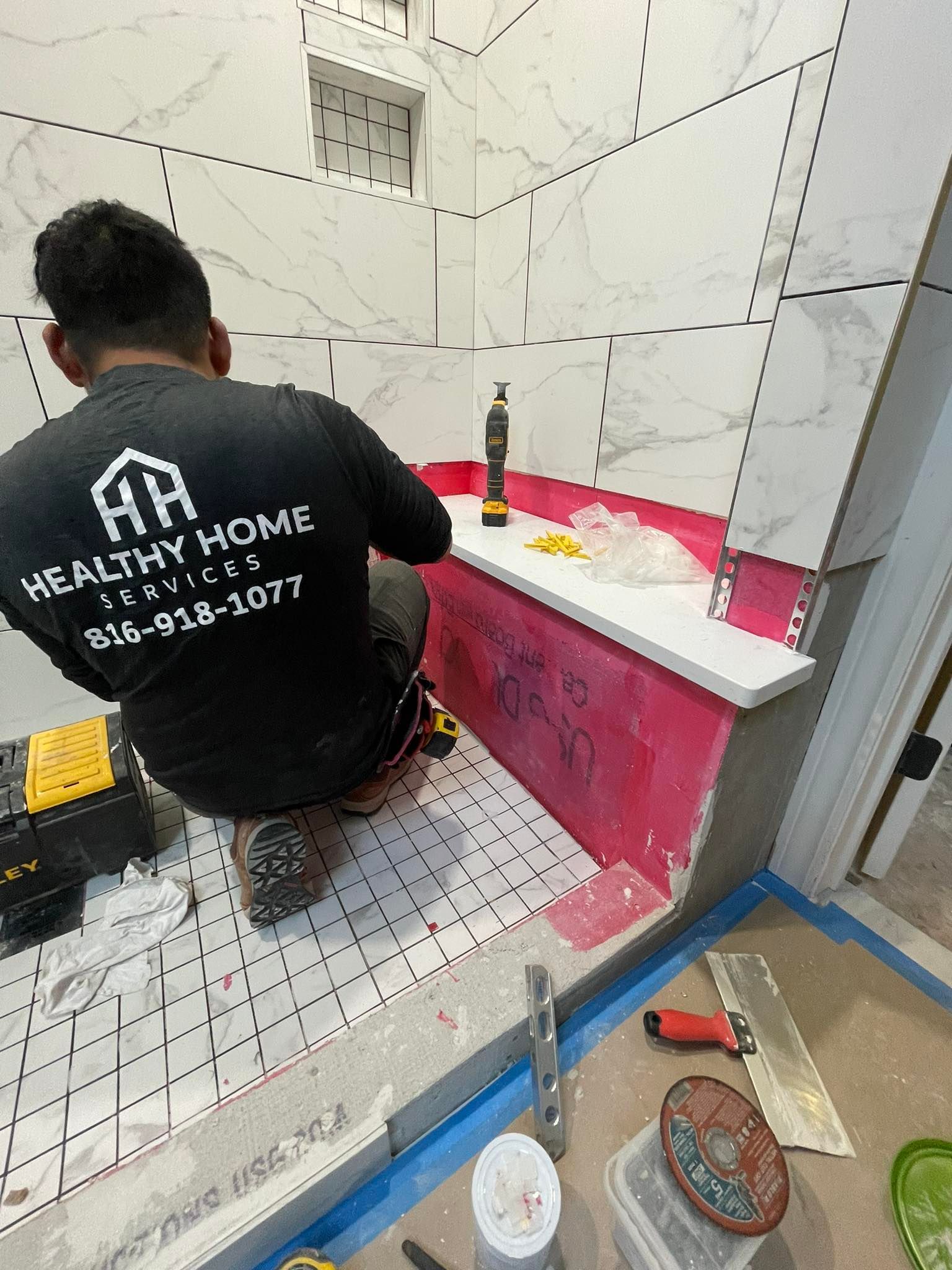 A man is kneeling on the floor in a bathroom.