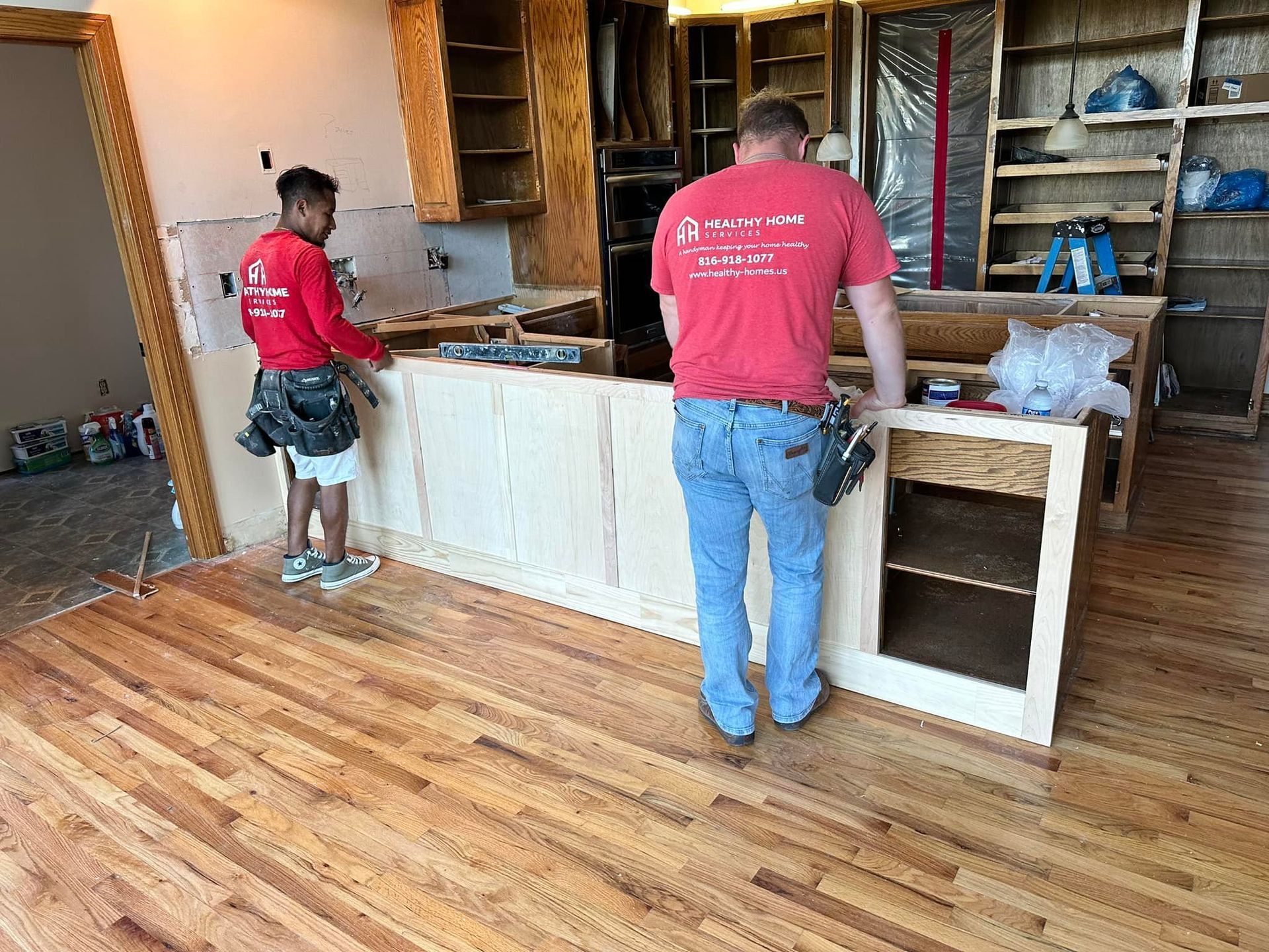 Two men are working on a kitchen in a house.