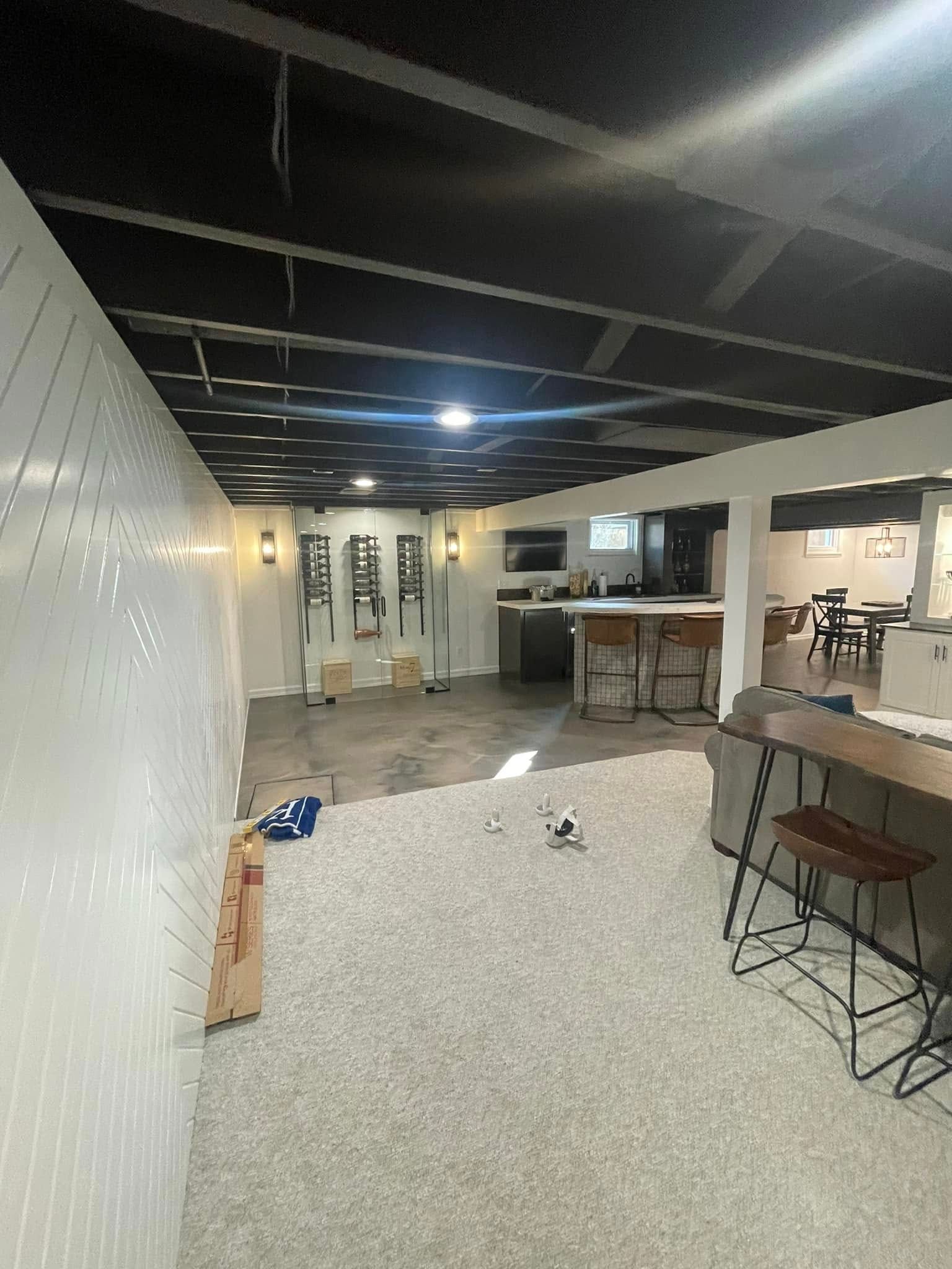 A large empty room with a black ceiling and a white wall.