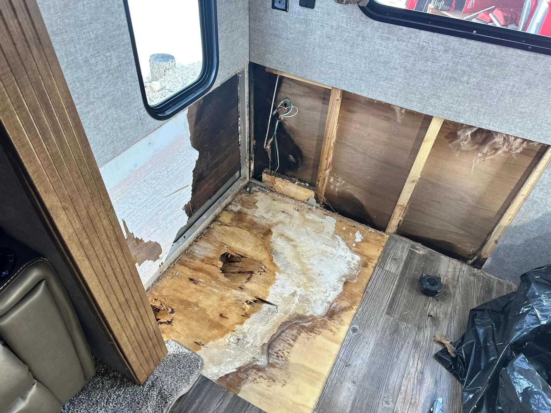 A camper with a hole in the wall and a hole in the floor.