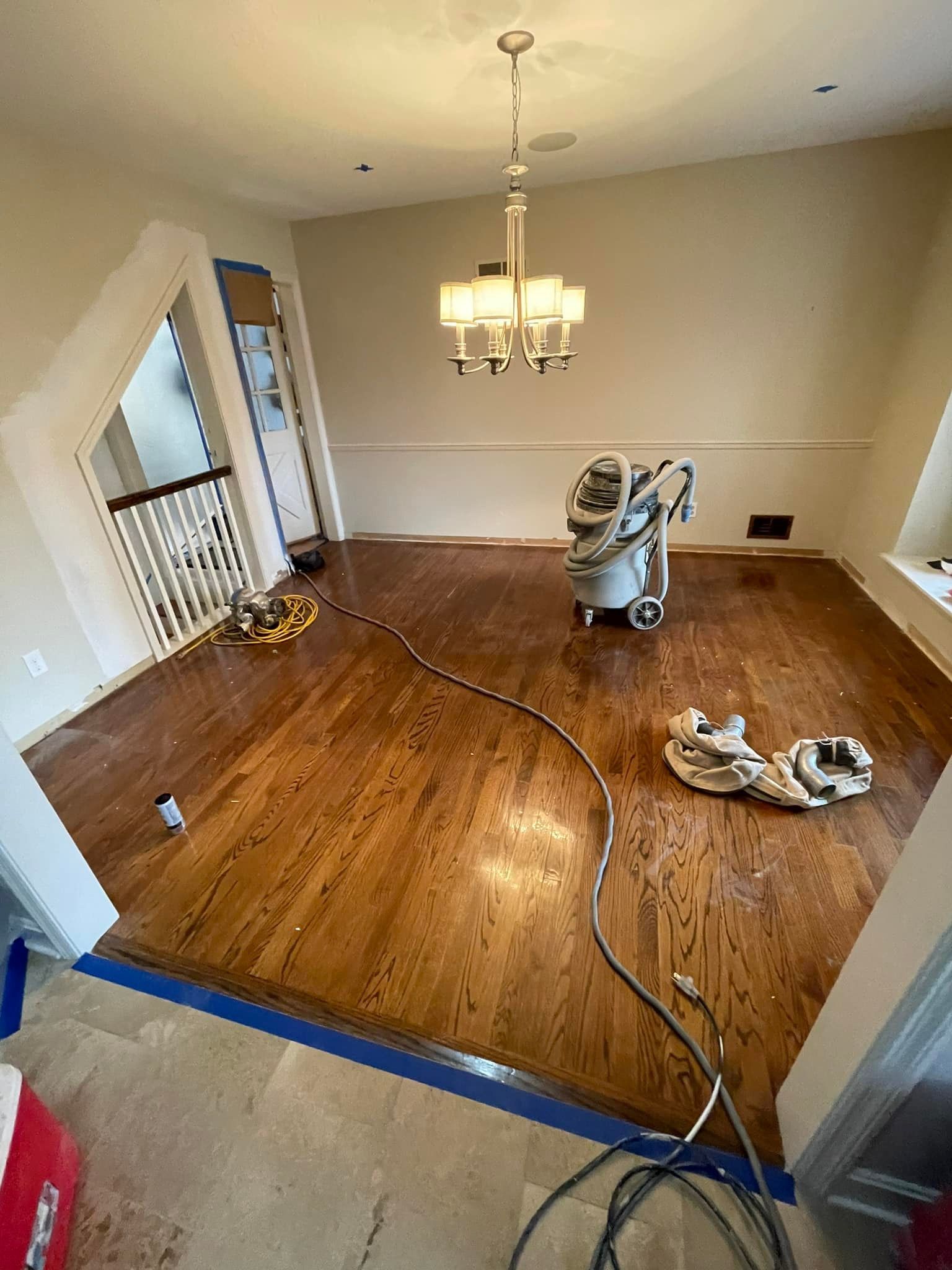 A vacuum cleaner is sitting on a wooden floor in a dining room.