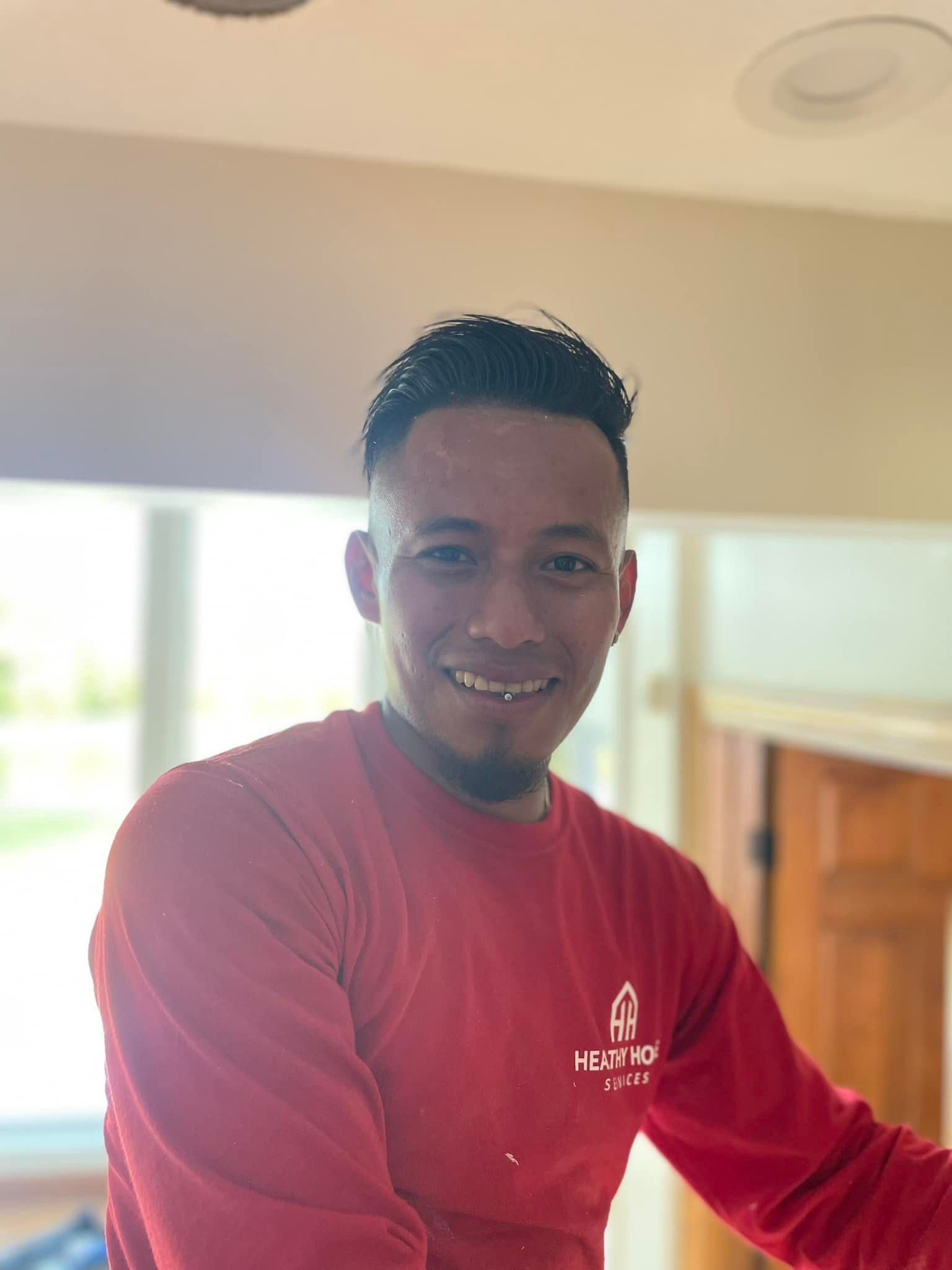 A man in a red shirt is smiling for the camera.