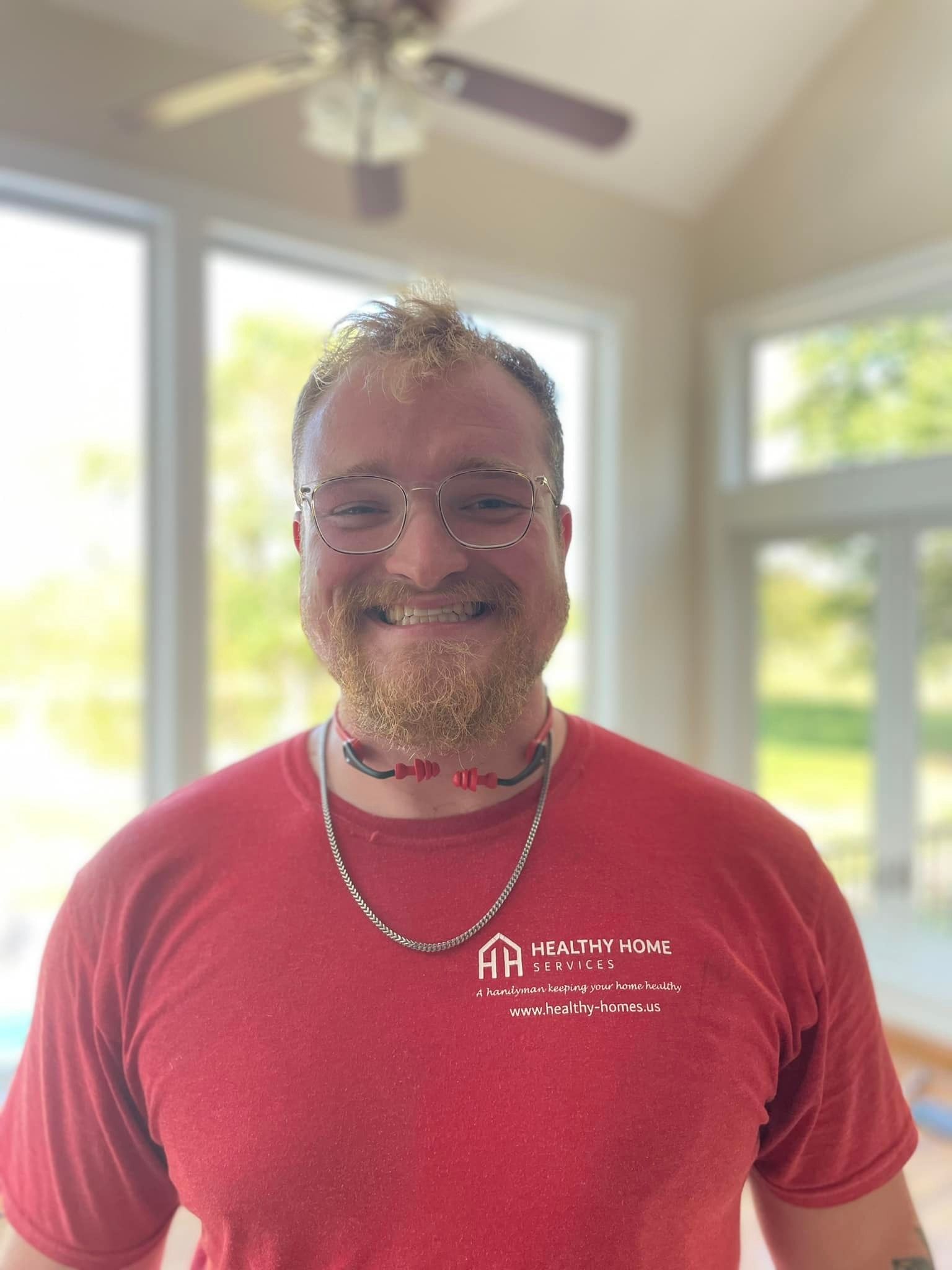 A man wearing glasses and a red shirt is smiling for the camera.