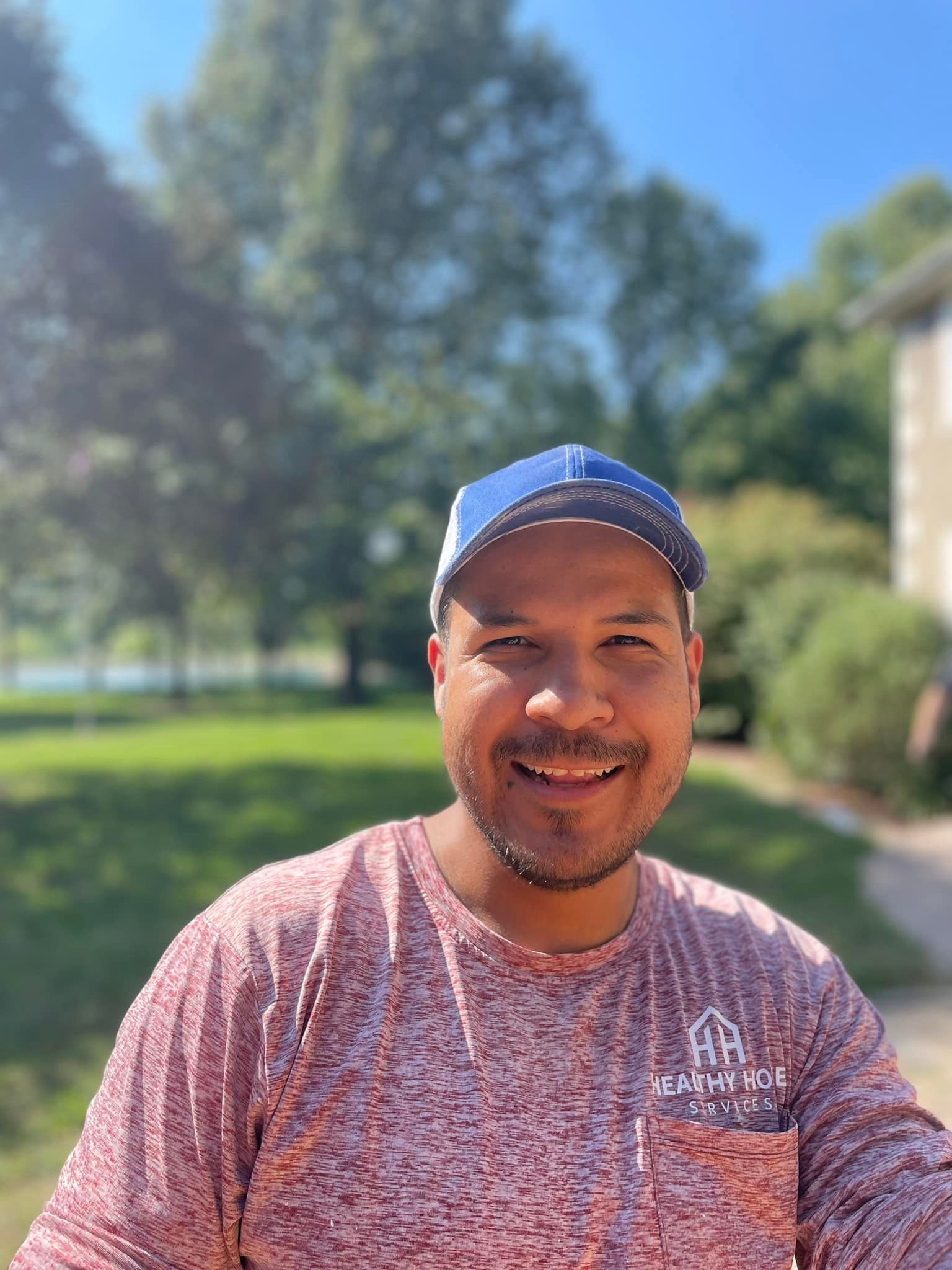 A man wearing a baseball cap and a red shirt is smiling for the camera.