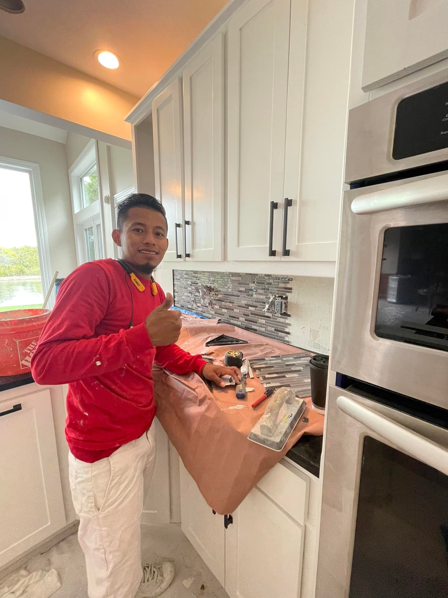 A man in a red shirt is standing in a kitchen.