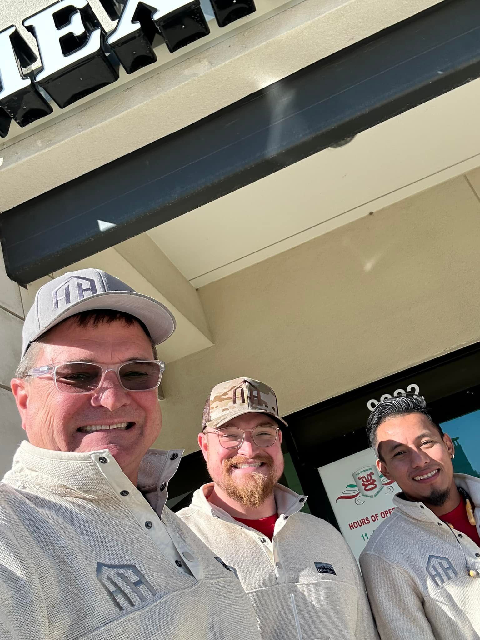 Three men are posing for a picture in front of a building.