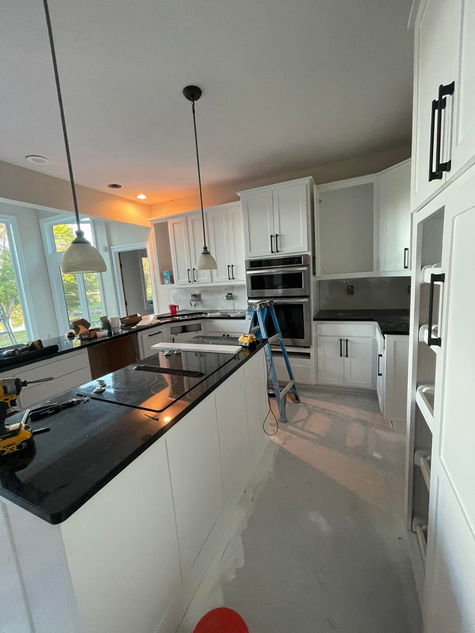 A kitchen with white cabinets and black counter tops is being painted.