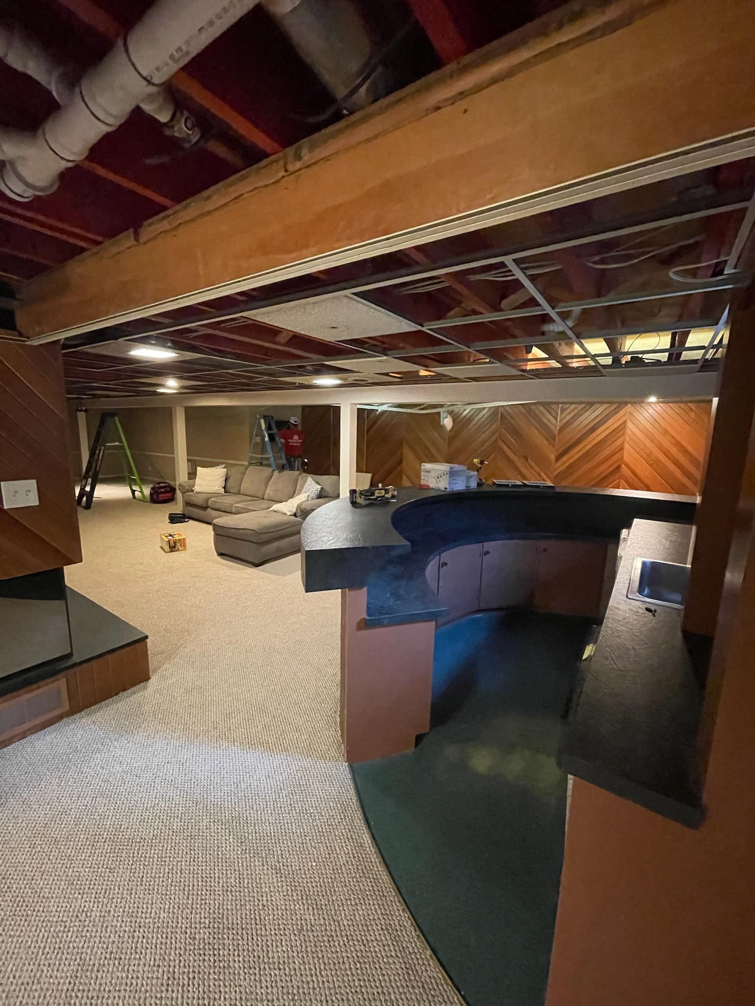 A living room in a basement with a couch and a table.
