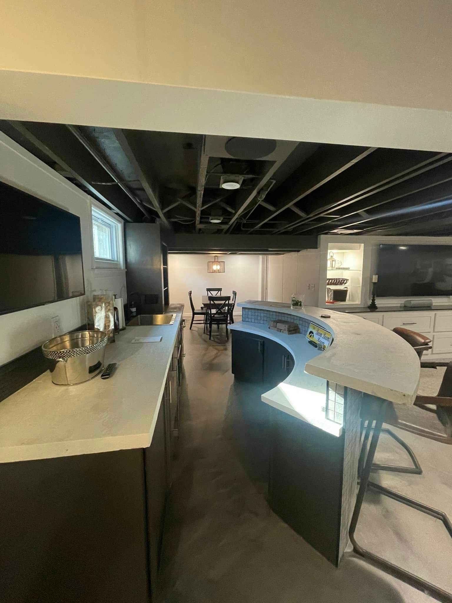 A kitchen in a basement with a table and chairs.