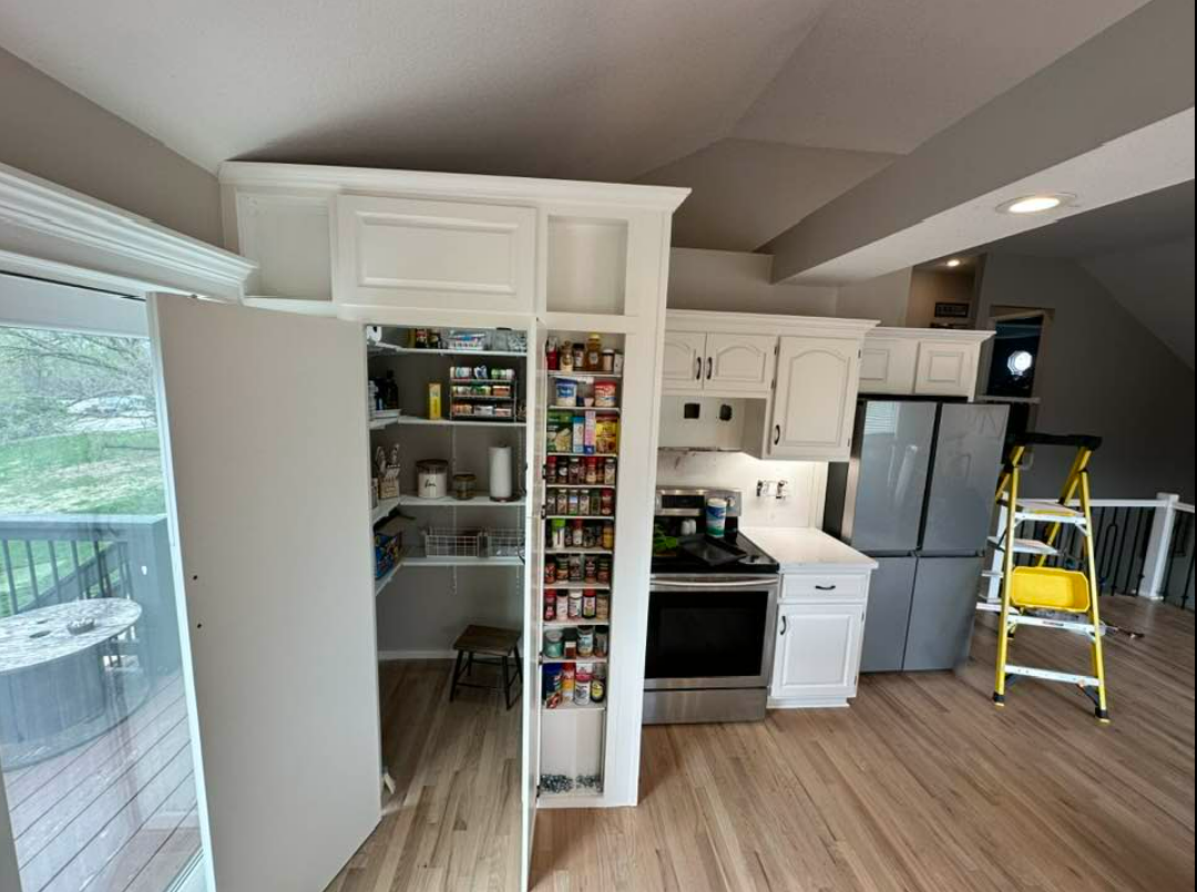 A kitchen with a pantry , stove , refrigerator and a ladder.