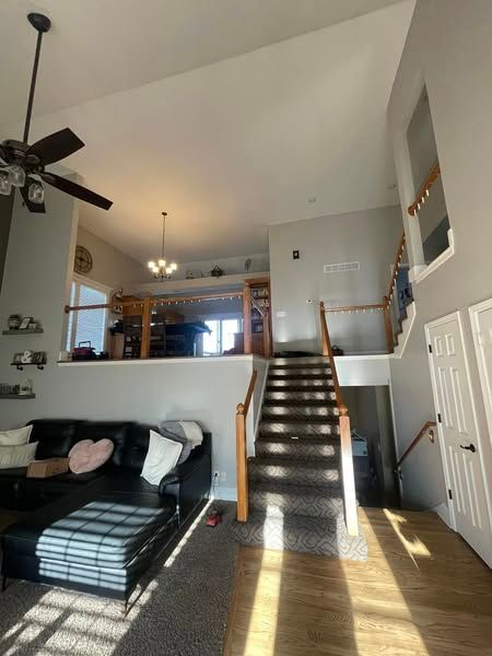 A living room with a couch , stairs and a ceiling fan.