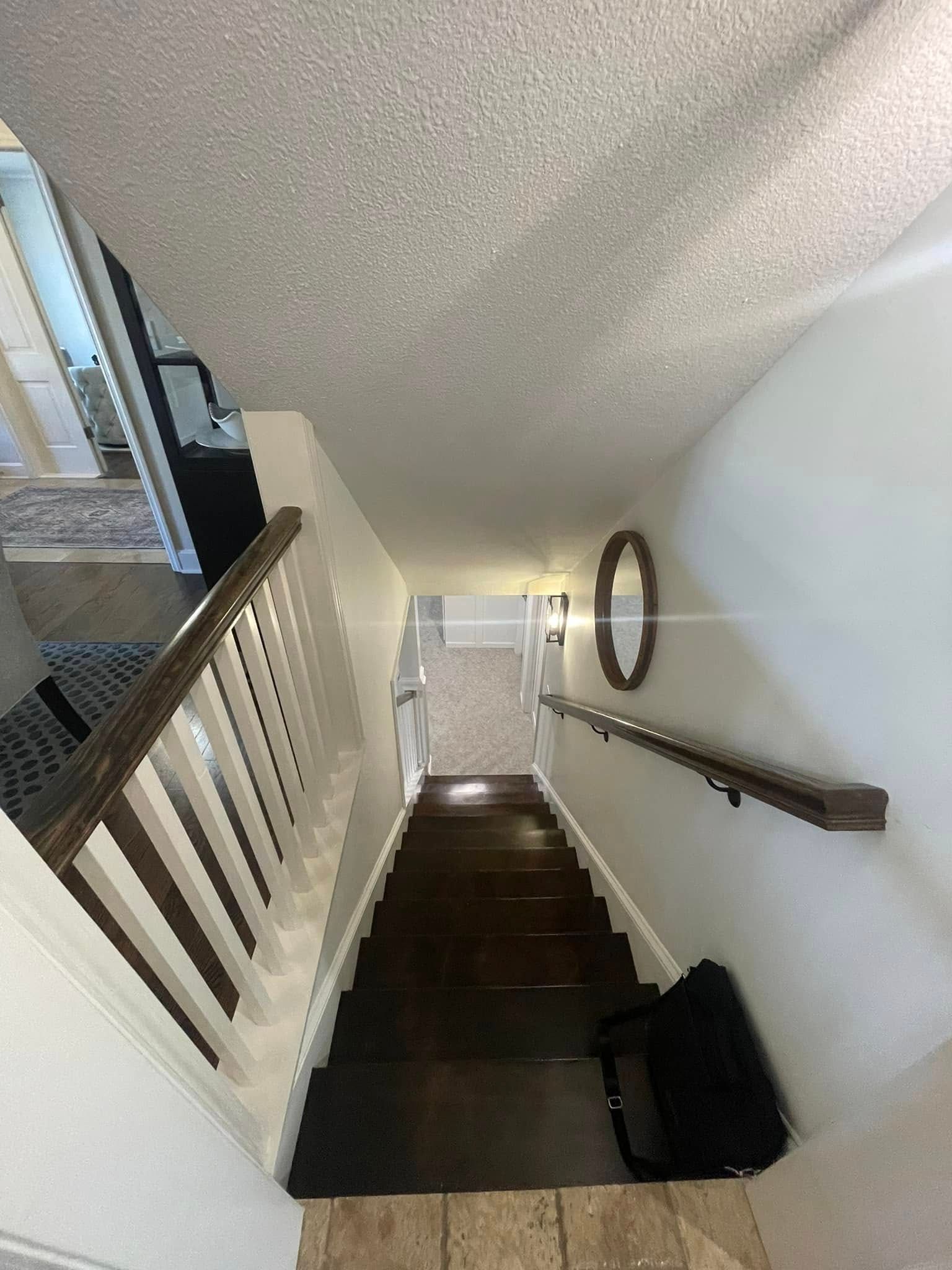 A staircase leading up to the second floor of a house with a mirror on the wall.