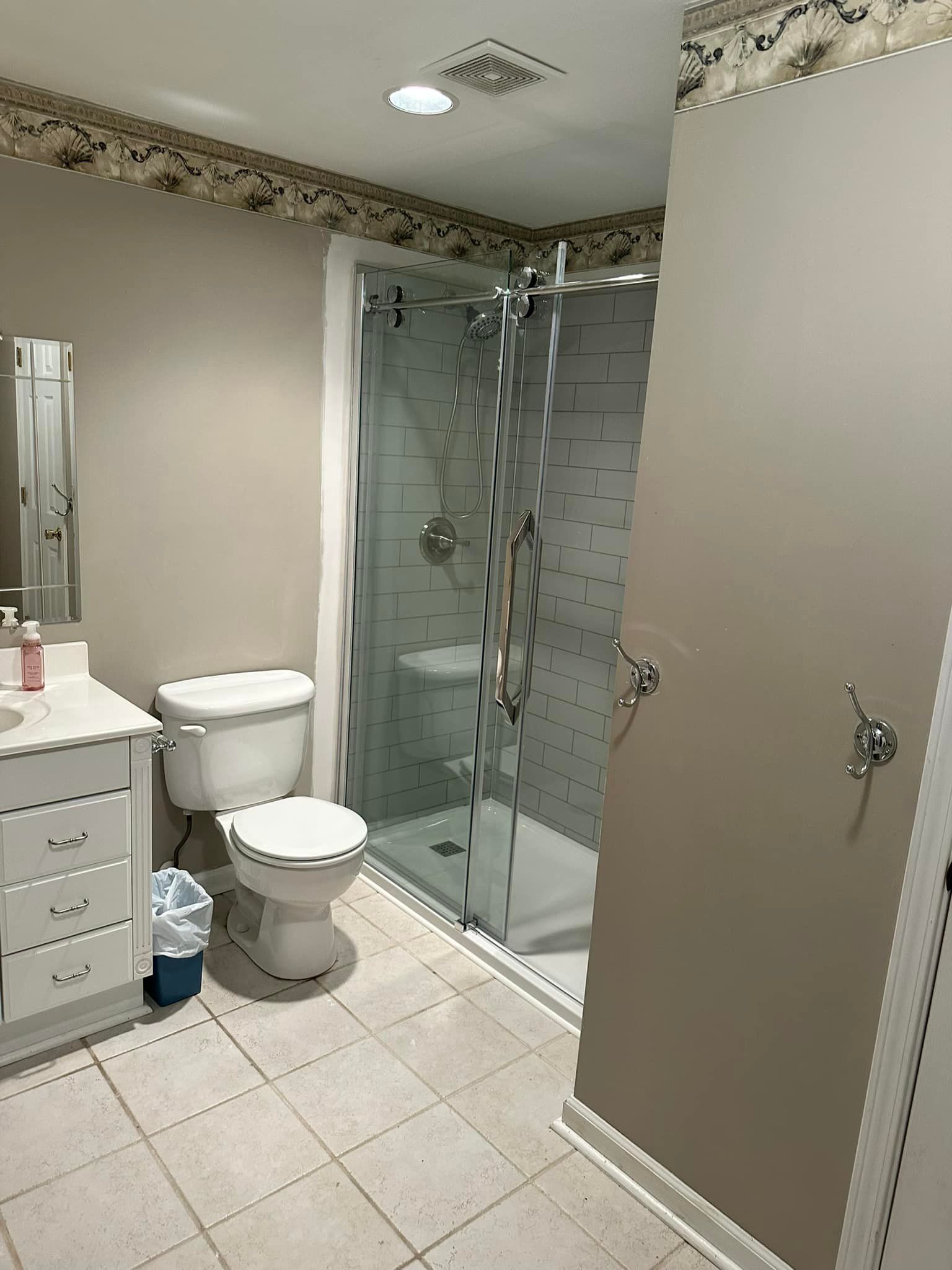 A bathroom with a toilet , sink , shower and mirror.
